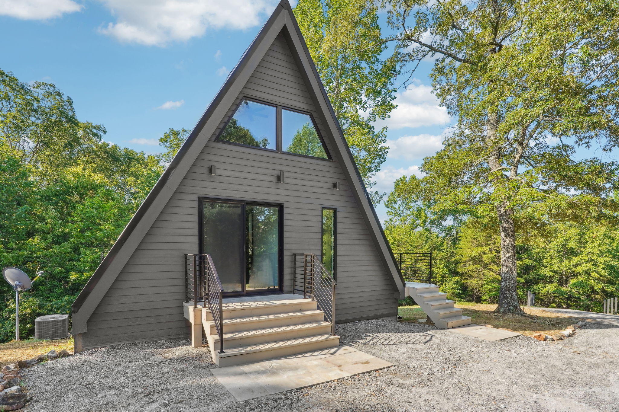 Frontal view of a modern style A-Frame home. The home has gray wood siding,
